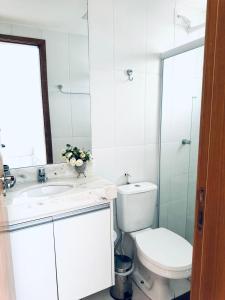 a white bathroom with a toilet and a sink at Condomínio Porto Smeralda in Camacari