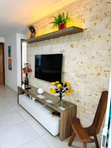 a living room with a television on a brick wall at Condomínio Porto Smeralda in Camacari