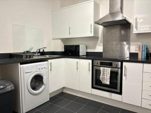una cucina con armadi bianchi e una lavatrice/asciugatrice di Stunning apartment in Reading near City Centre & Train Station a Reading