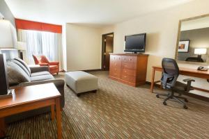 a hotel room with a couch and a desk with a television at Drury Inn & Suites St. Louis Creve Coeur in Creve Coeur