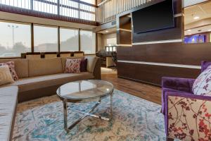 a lobby with a couch and a table and a tv at Drury Inn & Suites Louisville East in Louisville