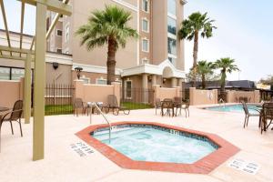 ein Pool mit Tischen und Stühlen und ein Gebäude in der Unterkunft Drury Inn & Suites McAllen in McAllen