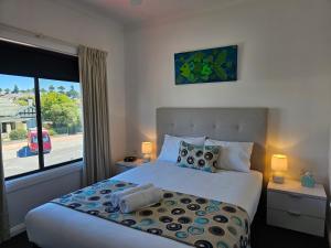 a bedroom with a bed and a large window at Aart Apartments in Port Lincoln
