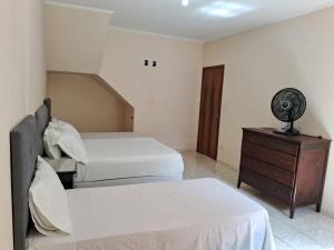 1 Schlafzimmer mit 2 Betten und einer Kommode mit einem Ventilator in der Unterkunft Casa Sta Amélia 3 quartos, 3 banheiros c/ garagem in São Roque