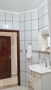 ein weißes Badezimmer mit Waschbecken und Spiegel in der Unterkunft Casa Sta Amélia 3 quartos, 3 banheiros c/ garagem in São Roque