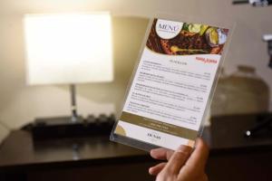 una persona che tiene in mano un menu di Hotel Dunas Near Consulate a Ciudad Juárez