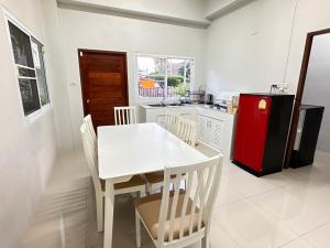 a kitchen with a white table and a red refrigerator at ประกายทอง พูลวิลล่า 