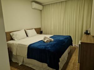 1 dormitorio con 1 cama con manta azul en Suíte Luxo Via Premiere, en Río de Janeiro