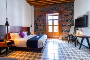 een slaapkamer met een bed, een bureau en een televisie bij Casa de la Luz Hotel Boutique in Mexico-Stad