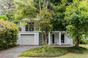 a white house with a garage and trees at Narrawallee Beach House in Narrawallee