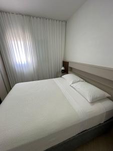 a bedroom with a large white bed with a window at Residencial 04 Monte Carlo em São Roque in São Roque