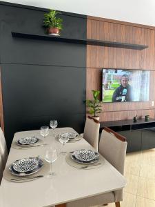 una mesa con platos y copas de vino y una TV en Residencial 04 Monte Carlo em São Roque, en São Roque