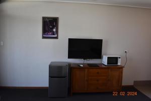 a television on a wooden dresser with a microwave at Coonawarra Motor Lodge in Penola