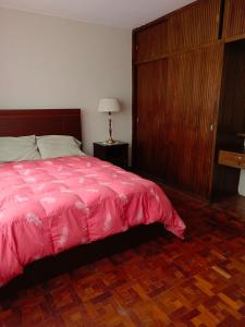 a bedroom with a pink bed and a wooden cabinet at Departamento Encinas in La Paz