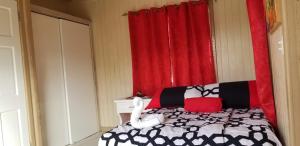 ein Schlafzimmer mit einem Bett und einem roten Vorhang in der Unterkunft CNP Apartments in Saint Johnʼs