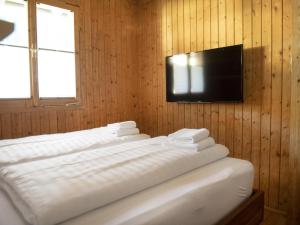 Cette chambre dispose d'un lit et d'une télévision sur un mur en bois. dans l'établissement Ferienhaus mit Weitblick, à Pill