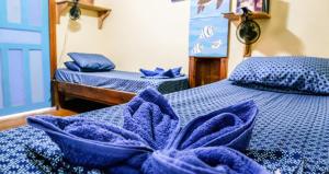a room with two beds with blue sheets and pillows at Roatan Backpackers' Hostel in Sandy Bay