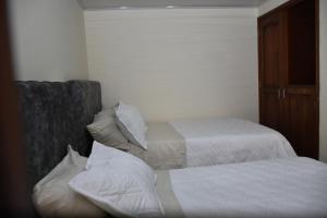 um quarto com 2 camas com lençóis brancos e almofadas em Confortable apartamento cerca de la plaza principal em Villa de Leyva