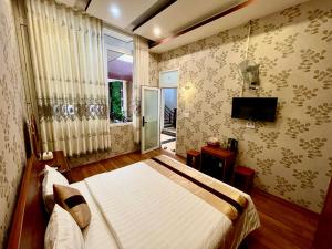 a bedroom with a bed and a window and a television at HOTEL MINH LÂM 2 in Pleiku