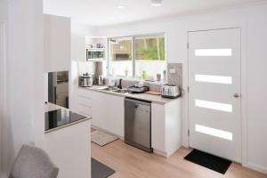 a white kitchen with a sink and a counter at Fully renovated 3 bedroom house & Free Parking in Gold Coast