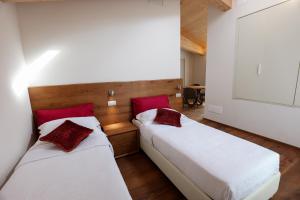 2 letti in una camera con cuscini bianchi e rossi di Antica Colombaia a San Marino