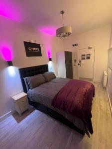 a bedroom with a bed with purple lights on it at CHEERZ Apartments in Aberdeen