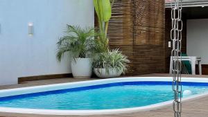 una piscina con macetas junto a una casa en Casa 4 quartos piscina praia Mariscal Bombinhas SC, en Bombinhas