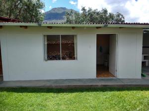 a white house with a window in a yard at Casa con jardín y vista a las montañas Pisac in Pisac