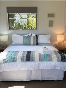 a bedroom with a large white bed with a window at Sea View Apartment in Whangaparaoa