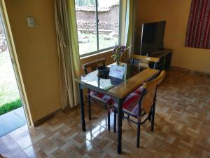 mesa de comedor con sillas y TV en Casa con jardín y vista a las montañas Pisac, en Písac