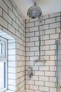 een douche in een badkamer met witte metrotegels bij REFURBISHED QUIET 3 BEDROOM FLAT BY HIGH STREET,TRAMS and BUSES - OR 30 MINS WALK TO CENTRE in Edinburgh