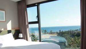 a bedroom with a bed and a view of the ocean at Grand Mer Hotel Seogwipo Ocean in Seogwipo