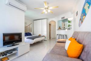 sala de estar con sofá, TV y cama en Oasis costero a pie de mar, en Algarrobo