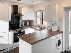 a kitchen with white cabinets and a wooden counter top at Isle View - 28284 in Broadford