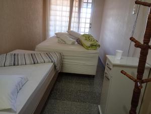 a small bedroom with two beds and a window at Santa Helena Pousada in Cachoeira Paulista
