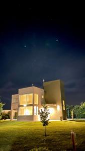 uma casa à noite com uma árvore em frente em Casa Calma Puerto del Aguila em Potrero de Garay