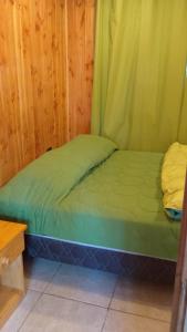 a small green bed in a wooden room at Cabañas Privadas en Pucon in Pucón