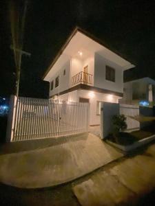 a white house with a white picket fence at night at Time To Sleep - Casa Ala Una in Butuan