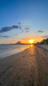 una spiaggia con il tramonto in lontananza di Apartamento sem vista ao mar, à 15 metros da praia de Piúma a Piúma