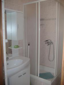 La salle de bains est pourvue d'un lavabo blanc et d'une douche. dans l'établissement Apartments by the sea Privlaka, Zadar - 22380, à Privlaka