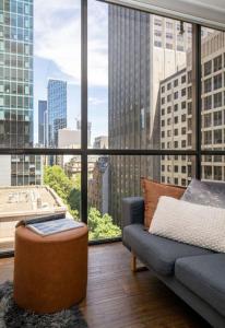 - un salon avec un canapé et une grande fenêtre dans l'établissement Bright City Views Melbourne Central Penthouse on Collins, à Melbourne