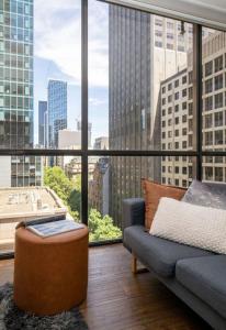 a living room with a couch and a large window at Bright City Views Melbourne Central Penthouse on Collins in Melbourne