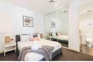 a white bedroom with a bed and a bathroom at Bright City Views Melbourne Central Penthouse on Collins in Melbourne