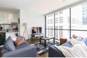 a living room with a blue couch and a large window at Bright City Views Melbourne Central Penthouse on Collins in Melbourne