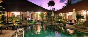 a swimming pool in a resort with chairs and trees at Stana Puri Gopa Hotel in Sanur