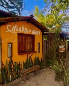una casa amarilla con un banco delante en Pousada Lumar, en Caraíva
