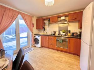 a kitchen with wooden cabinets and a large window at Payler House Sheffield-WiFi -Large Parking Space-cozy 4 bedrooms in Sheffield