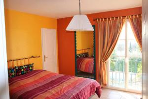 a bedroom with orange walls and a bed and a window at Villa élégante à Villelaure + Clim in Villelaure