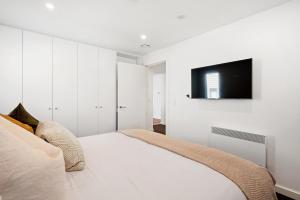 une chambre avec un lit et une télévision sur un mur dans l'établissement Lakeside Luxury 2 Bedroom Apartment, à Wanaka