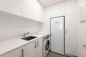 eine weiße Küche mit einer Spüle und einem Kühlschrank in der Unterkunft Lakeside Luxury Studio Apartment in Wanaka